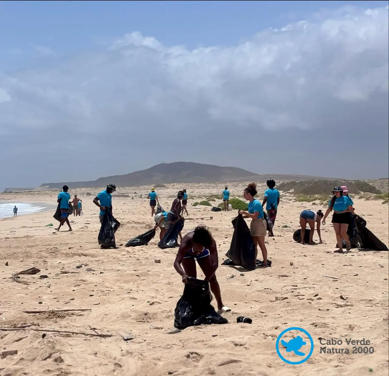 Voluntarios con camisetas azules recogiendo residuos en una playa de Cabo Verde
